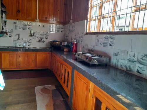 a kitchen with wooden cabinets and a counter top at Odyssey Stays Mechuka in Bāsār
