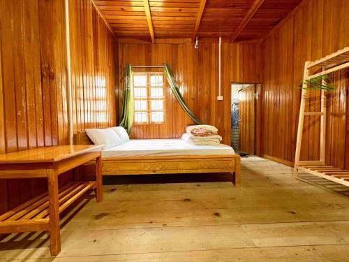a bedroom with a bed in a wooden room at Odyssey Stays Mechuka in Bāsār