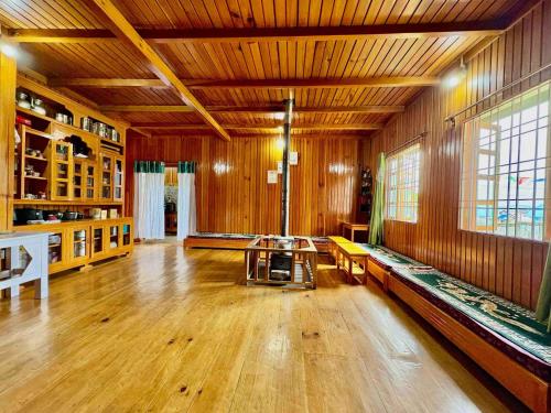 a large room with wooden walls and a wooden floor at Odyssey Stays Mechuka in Bāsār