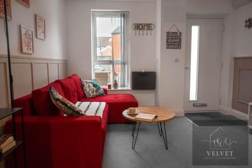 a living room with a red couch and a table at Cheerful 1-bedroom home with free parking, WiFi in Swansea