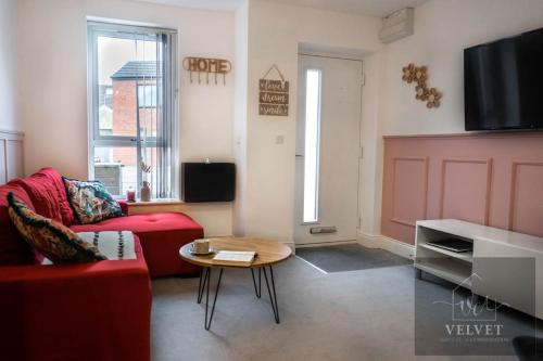 a living room with a red couch and a table at Cheerful 1-bedroom home with free parking, WiFi in Swansea