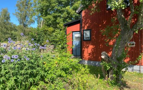 a red cabin with a garden with purple flowers at 2 Bedroom Stunning Home In Habbestorp 