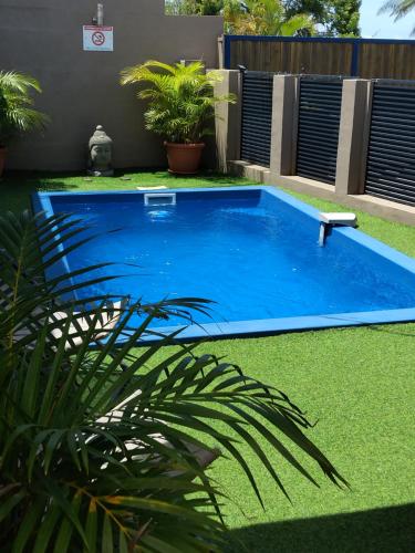 a blue swimming pool in a yard with grass at Ti kaz Tata du sud Sauvage in Saint-Joseph