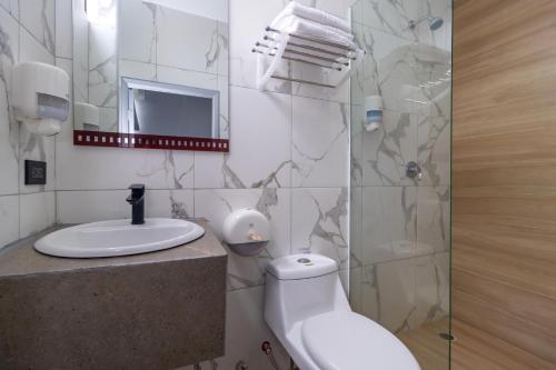 a bathroom with a toilet and a sink and a shower at Hotel Presidente Internacional in Guayaquil