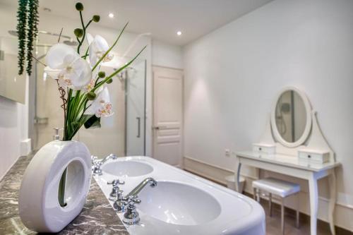 a white bathroom with a sink and a vase of flowers at Bedroom 3 - Spacious and Bright - COLIVING in Ferney-Voltaire