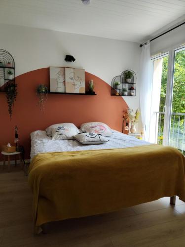 a bedroom with a bed with an orange wall at Chez Lily et Fred in Châlons-en-Champagne