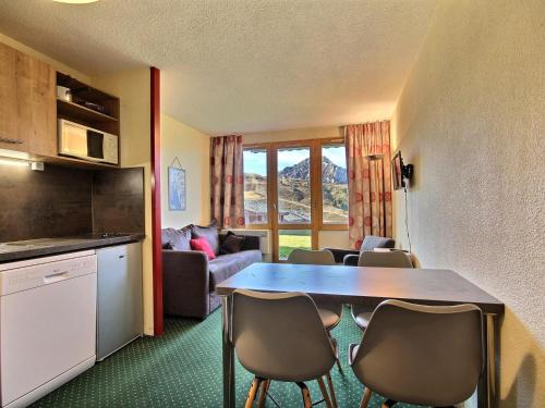 une cuisine et un salon avec une table et des chaises dans l'établissement Studio accessible PMR au pied des pistes avec terrasse - FR-1-455-24, à Belle Plagne
