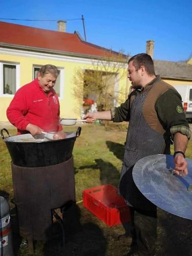 a man and a woman cooking food on a grill at Barangoló vendégház in Bárdudvarnok