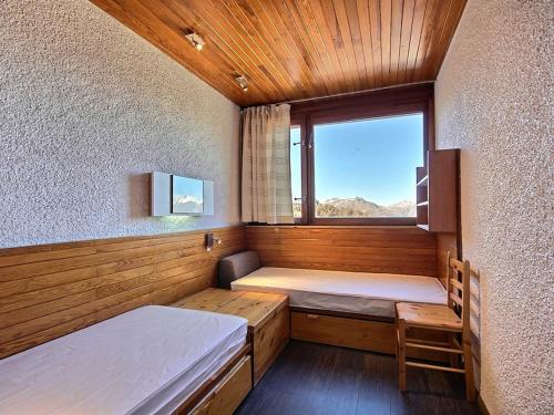 une petite chambre avec deux lits et une fenêtre dans l'établissement Appartement cosy au pied des pistes avec balcon et équipements modernes - FR-1-455-61, à La Plagne