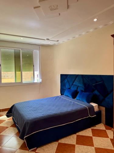 a bedroom with a bed with a blue headboard at Évasion à deux pas de la mer in Saïdia