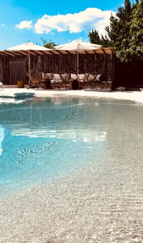 a pool of water with chairs and umbrellas at Domaine FINCA LESSYA, Lodge insolite & SPA in Mauguio