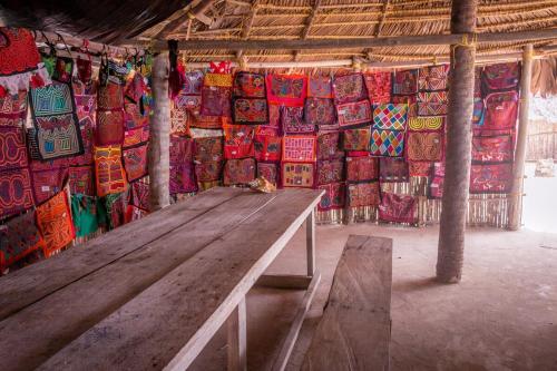 a wooden bench in front of a wall of colorful bags at Cabaña Romantica frente al mar de isla Chichime Guna Yala in Wagsalatupo Grande