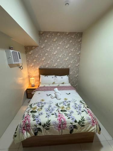a bedroom with a bed with a floral bedspread at Brenthill Condominium in Baguio