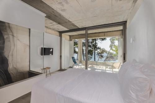une chambre avec un lit blanc et une grande fenêtre dans l'établissement Pefka Luxury Homes, à Kalivia Poligirou