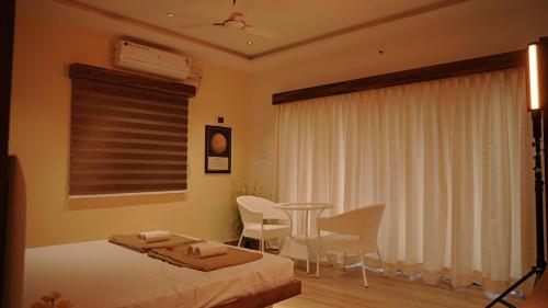 a bedroom with a bed and a table and chairs at 9 planets resort in Gangolli