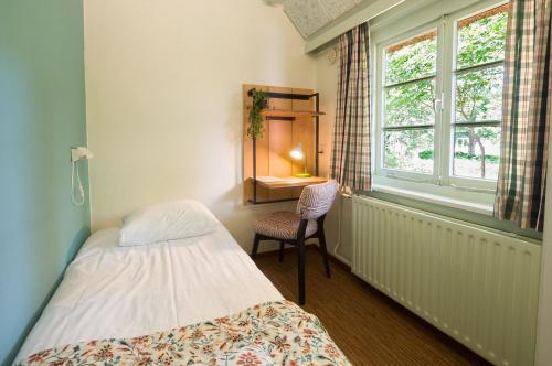 a bedroom with a bed and a chair and a window at Hostel Landgoed de Kalenberg in Barchem