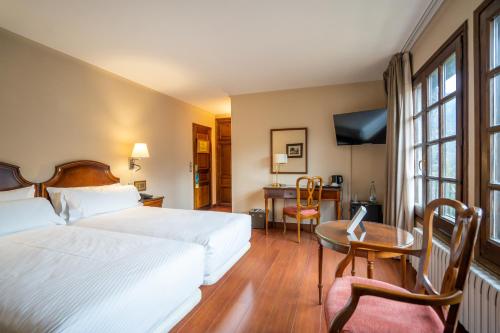 a hotel room with a bed and a table and a desk at Abba Xalet Suites Hotel in Sispony