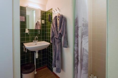 a green tiled bathroom with a sink and a shower at Hostel Landgoed de Kalenberg in Barchem