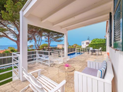 Un patio al aire libre con sillas blancas y una mesa. en Villa Ty Bihan, en Binibeca