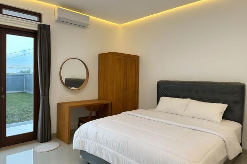 ein Schlafzimmer mit einem Bett, einem Spiegel und einem Fenster in der Unterkunft Casa Nika Kerobokan in Kerobokan