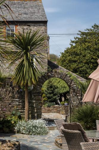 a stone building with a palm tree in a yard at The Old Mill House in Padstow
