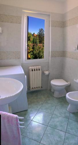 a bathroom with a sink and a toilet and a window at Casa Mariarosa in Maccagno Inferiore