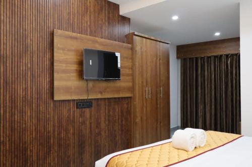 a bedroom with a bed and a tv on a wall at Rhythm Stays in Munnar