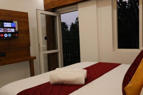 a bedroom with a bed and a window with a television at Rhythm Stays in Munnar