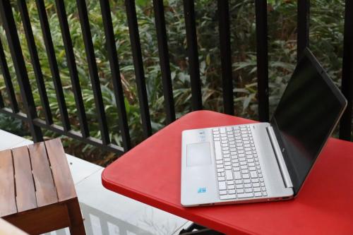 a laptop computer sitting on a red table on a balcony at Rhythm Stays in Munnar