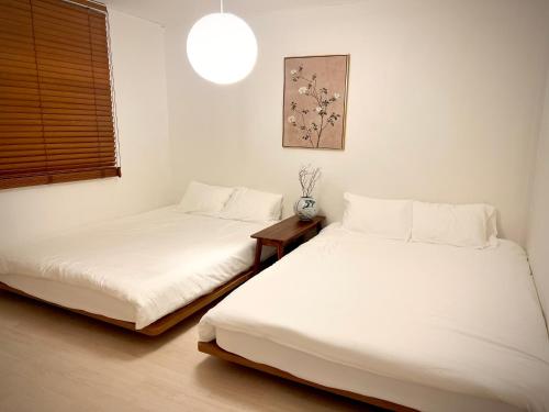 two beds in a room with white walls at hongdae hanriver habjung sinchon in Seoul
