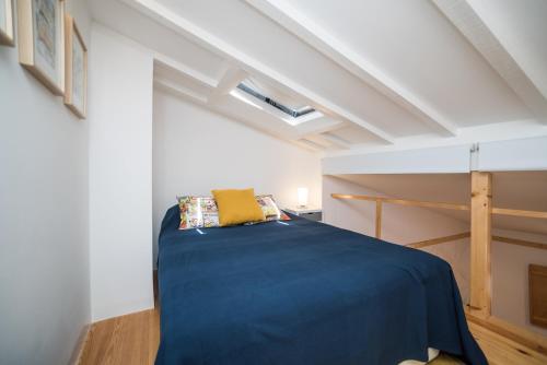 una camera da letto con un letto blu in una stanza bianca di Feel Alfama Apartment a Lisbona