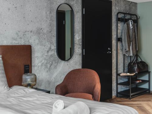 a bedroom with a bed and a chair and a mirror at H28 - Hotel, Apartments and Suites by UHANDA in Tampere