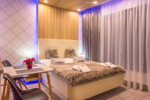 a bedroom with a bed and a desk and a table and chairs at Štúdio A111 HREBIENOK in Vysoké Tatry