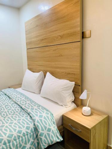 a bedroom with a bed and a wooden headboard at Eagle Nest Apartment and Hotel in Benin City