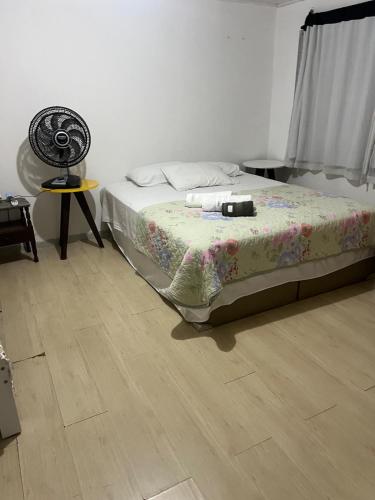 a bedroom with a bed and a fan on a wooden floor at Casa Camburi 1 in Vitória