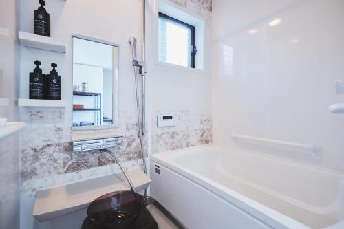a white bathroom with a tub and a sink at Little Seagull in Tateyama
