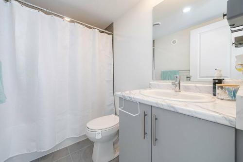 a white bathroom with a toilet and a sink at Modern Townhouse Rooftop Vibes in Oakville