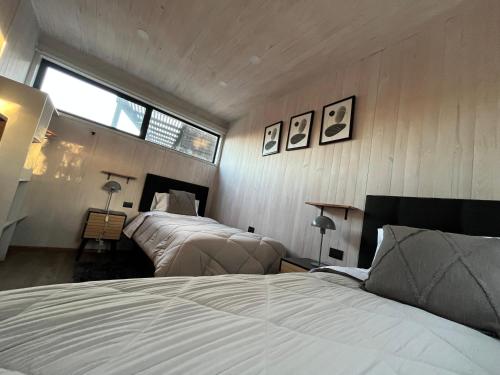 a bedroom with two beds and a window at Lodge KARKÚ in Pichilemu