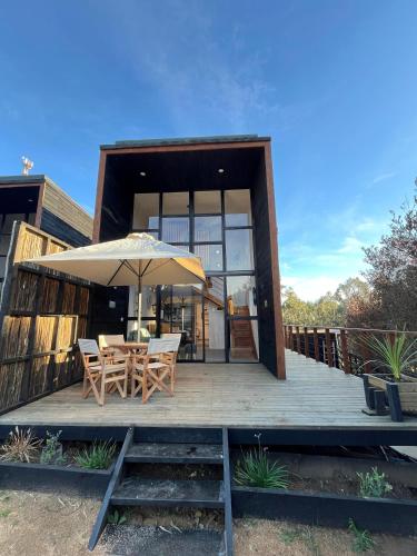 a wooden deck with a table and an umbrella at Lodge KARKÚ in Pichilemu