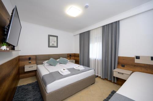 a hotel room with a bed and a television at Kollar D Guest House - Prenoćište ROOMS in Subotica