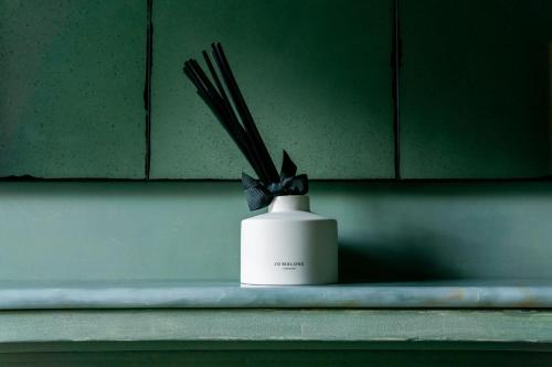a white vase with some sticks in it at Maison Rokxy - Luxury Apartments in London