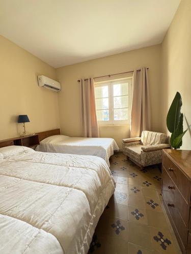 a bedroom with two beds and a chair and a window at Casa verde in Cañada Rosquín