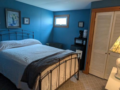 a bedroom with a bed with blue walls and a window at Logged Inn in Caroga Lake