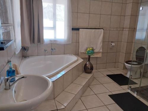 Un baño con bañera, lavabo e inodoro. en The Lion Room at Frederick's Place, en Pretoria
