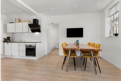 a kitchen and dining room with a wooden table and chairs at 2 Centralt beliggende og lyst indrettet lejlighed in Skagen