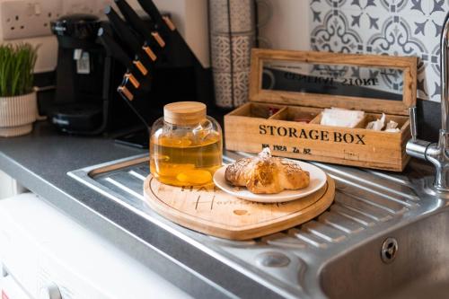 a chopping board with a jar of honey and a plate of food at Stylish Chalet 5min to Beach in Swansea