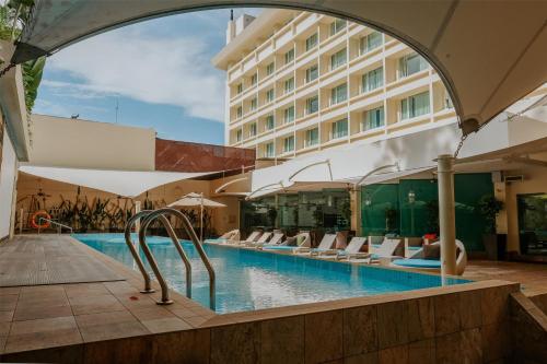 a swimming pool with chairs and a hotel at Radisson Hotel Brunei Darussalam in Bandar Seri Begawan