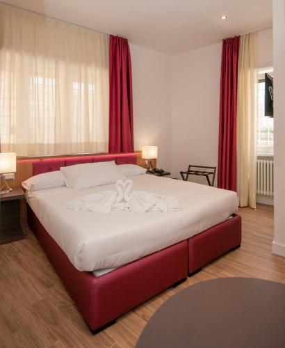 a large bed in a bedroom with red curtains at Vatican Relais Rome in Rome