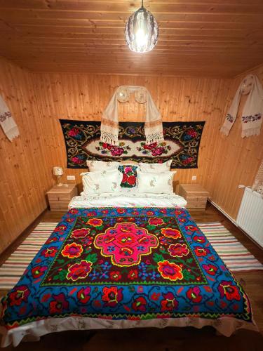 a bedroom with a bed with a colorful blanket on it at Casa de la ferma Mariuca in Berbeşti