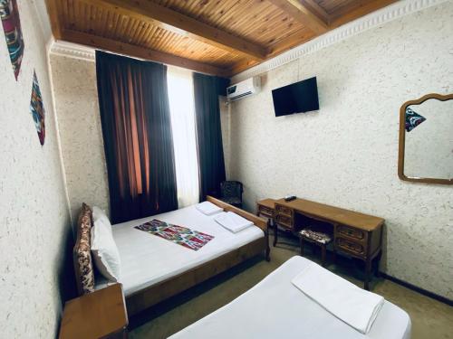 una stanza con un letto, una scrivania e una televisione di Omar Family Resort Mekhtar anbar str 45 a Bukhara